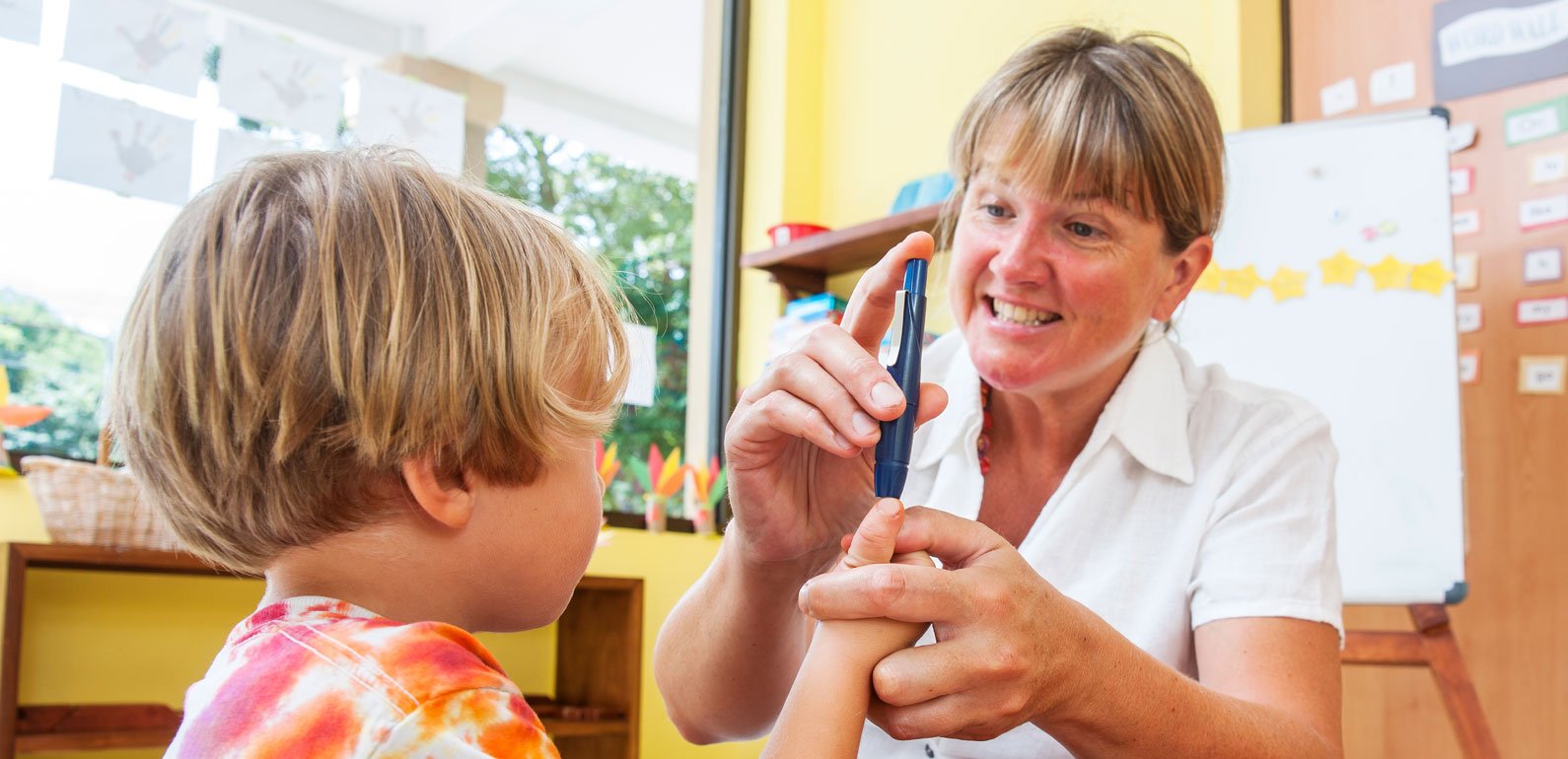 A health worker with a child holding a pen to their finger