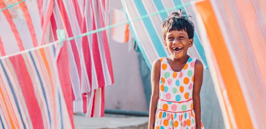 Sri Lankan girl smiling and standing amongst hanging blankets