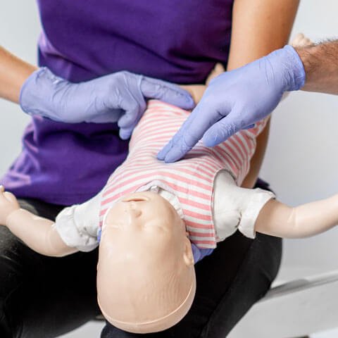Health worker demonstrating life saving techniques on a dummy that looks like a baby