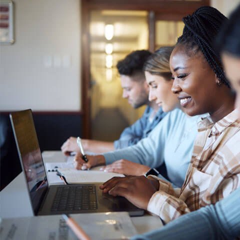 People sat at a desk with laptops in front of them