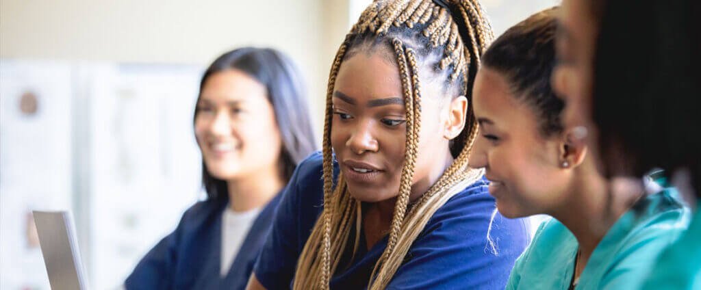 Group of healthcare workers looking at computers and learning