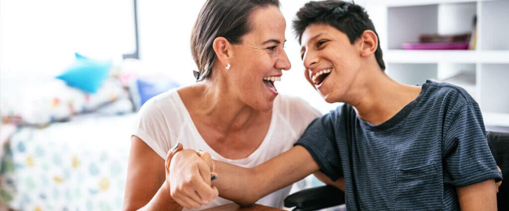 Adult and teenager in a wheelchair laughing together